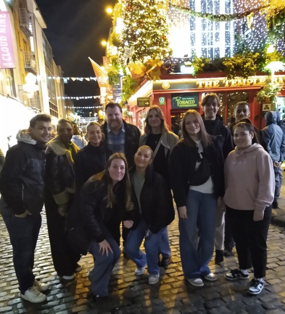 Photograph of students in Temple Bar, standing in front of pub lit up with Christmas lights