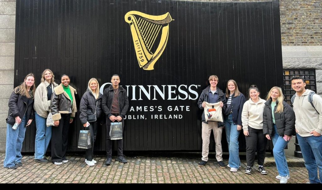 Group of students standing in front of delivery gates painted with Guinness logo at the Guinness Storehouse