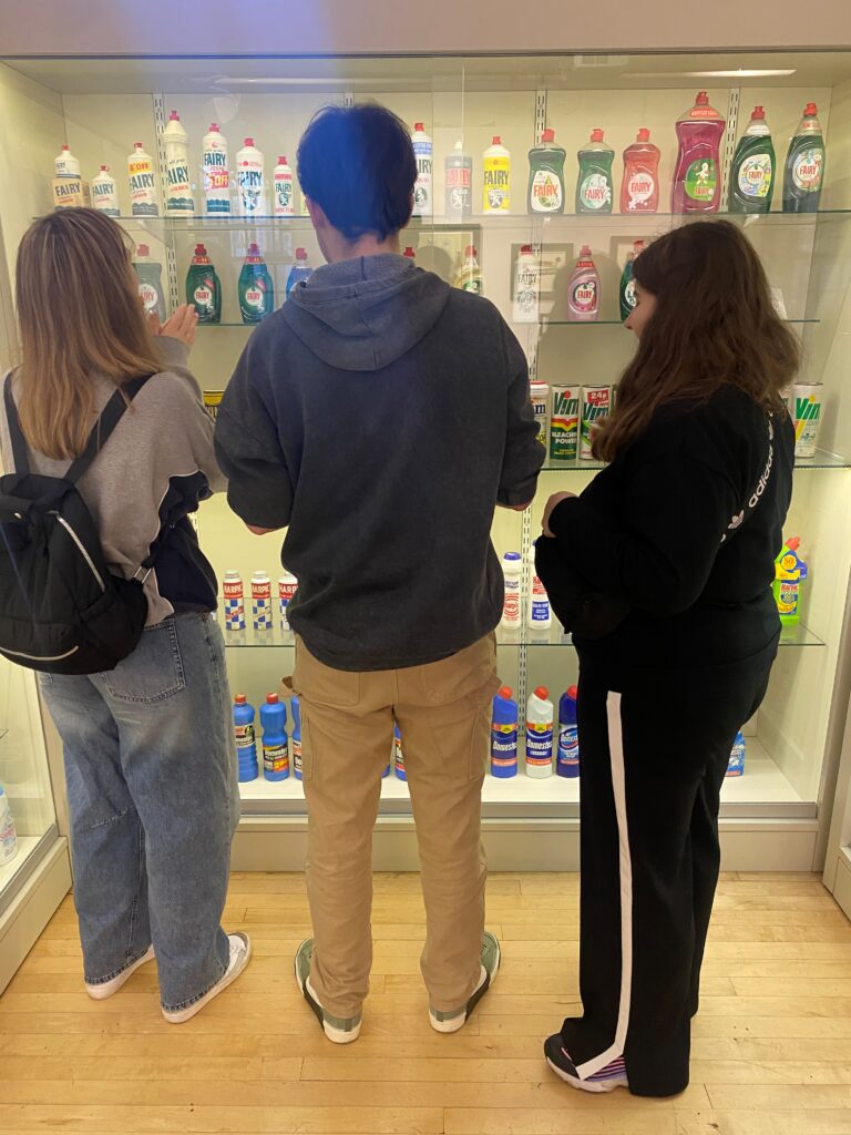 A photograph of students looking at display of branded household goods.